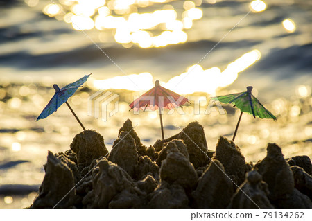 Three small beach umbrellas made of paper for cocktail stand in sand Three small beach umbrellas made of paper for cocktail stand in sand 79134262