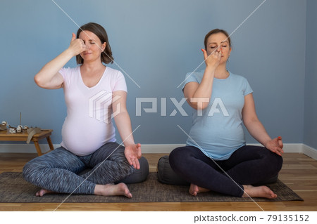 Pregnant fitness person practicing yoga at home. Prenatal Pranayama. Pregnant fitness person practicing yoga at home. Prenatal Pranayama. 79135152