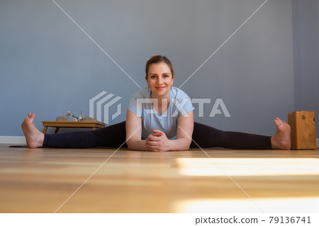 Pregnant woman working out doing Seated straddle posture, Upavishtha Konasana 79136741