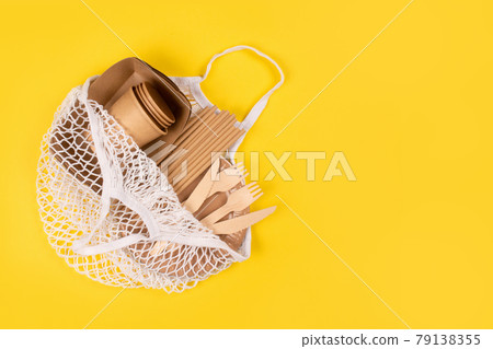 Eco-friendly tableware - kraft paper food cups, plates and containers with wooden cutlery in cotton bag on yellow background with copy space. Street food paper packaging, sustainable packaging concept 79138355
