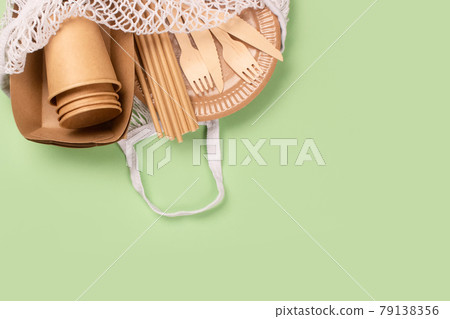 Eco-friendly tableware - kraft paper food cups, plates and containers with wooden cutlery in cotton bag on green background with copy space. Street food paper packaging, sustainable packaging concept 79138356