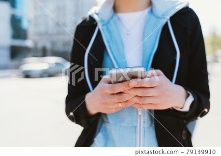 Close-up young woman in city using her smartphone 79139910