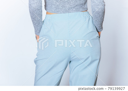 Rear view of young slender woman wearing gray long sleeve crop top 79139927