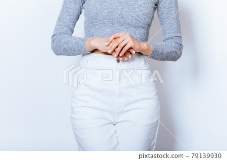 Close-up of folded arms of woman dressed in white high-waisted jeans 79139930