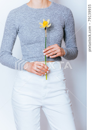 Unrecognizable young woman wearing white high waist jeans and gray crop top long sleeve 79139935