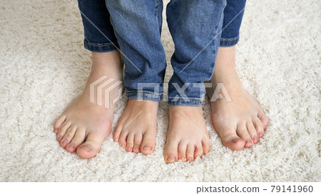Closeup of female and child feet standing on soft carpet and moving toes Closeup of female and child feet standing on soft carpet and moving toes 79141960