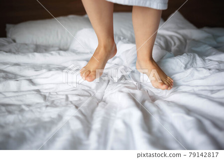legs of a little girl in a white robe jumping on the bed legs of a little girl in a white robe jumping on the bed 79142817