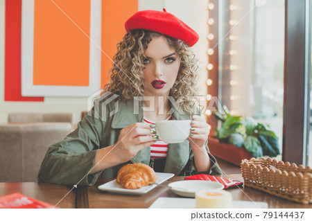 Pretty young woman sitting in the cafe with a cup of coffee 79144437