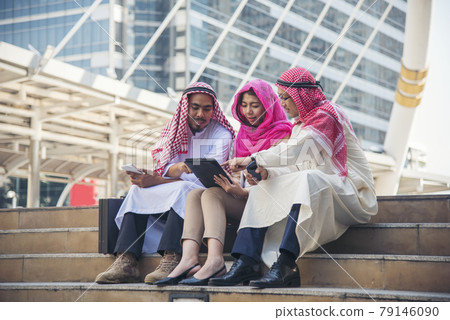 Digital marketing group arab people using smart tablet walking in  modern muslim UAE city touch screen discussion. Entrepreneur Asian people smile talking with boss outdoors 79146090