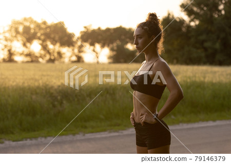 Young female runner, athlete is jogging at road in summer sunshine. Beautiful caucasian woman training, listening to music. Concept of sport, healthy lifestyle, movement, activity. Young female runner, athlete is jogging at road in summer sunshine. Beautiful caucasian woman training, listening to music. Concept of sport, healthy lifestyle, movement, activity. 79146379