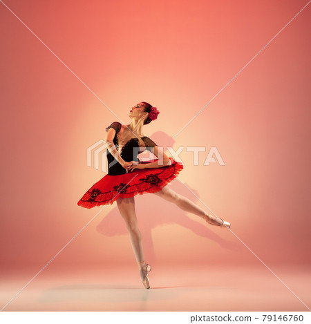 Young and incredibly beautiful ballerina is posing and dancing at red studio full of light. 79146760