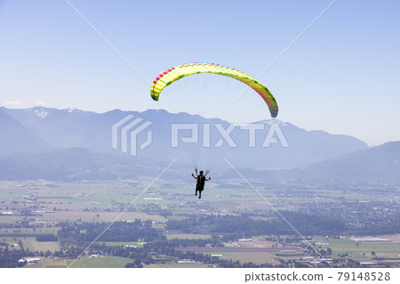 Adventurous Woman Flying on a paraglider around the Canadian Mountain Landscape Adventurous Woman Flying on a paraglider around the Canadian Mountain Landscape 79148528