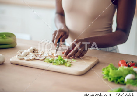 Hands of african american woman chopping vegetables with knife Hands of african american woman chopping vegetables with knife 79149191