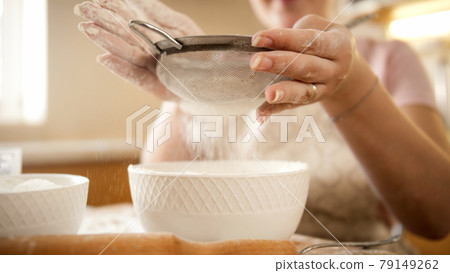 Sifting flour with metal sieve on domestic kitchen 79149262