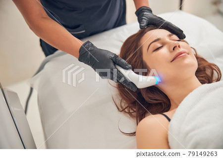 Beautician reducing wrinkles on cheeks of client Beautician reducing wrinkles on cheeks of client 79149263