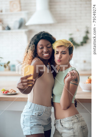 Two girlfriends hugging each other taking selfie on smartphone Two girlfriends hugging each other taking selfie on smartphone 79149274