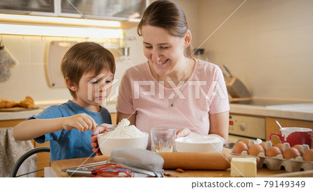 Little boy with young mother checking and weighting ingredients on digital scales. Children cooking with parents, little chef, family having time together, domestic kitchen. Little boy with young mother checking and weighting ingredients on digital scales. Children cooking with parents, little chef, family having time together, domestic kitchen. 79149349