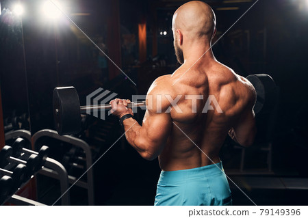 Strong muscly man wearing no shirt and lifting weights Strong muscly man wearing no shirt and lifting weights 79149396