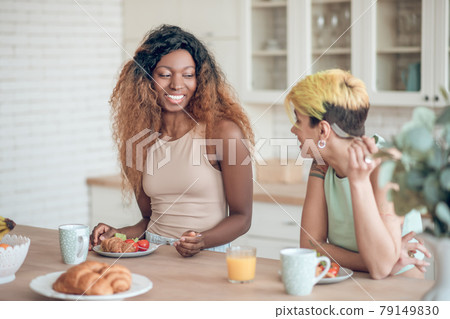 Laughing dark-skinned woman and girlfriend during breakfast Laughing dark-skinned woman and girlfriend during breakfast 79149830