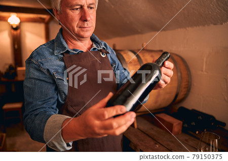 Male winemaker in apron holding bottle of wine 79150375