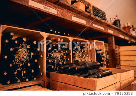 Glass bottles of wine stored in wooden crates and wine racks Glass bottles of wine stored in wooden crates and wine racks 79150398