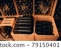 Glass bottles of wine stored in wooden crates and wine racks 79150401