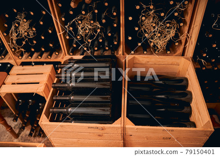 Glass bottles of wine stored in wooden crates and wine racks Glass bottles of wine stored in wooden crates and wine racks 79150401