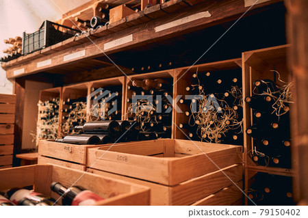 Bottles of wine stored in wooden crates and wine racks Bottles of wine stored in wooden crates and wine racks 79150402
