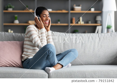 Domestic Pastime. Joyful African Female Listening Music In Wireless Headphones At Home 79151842