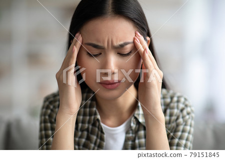 Closeup of young asian woman having headache, touching her temples 79151845