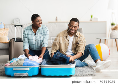Happy Black Spouses Packing Suitcase Together At Home 79151985