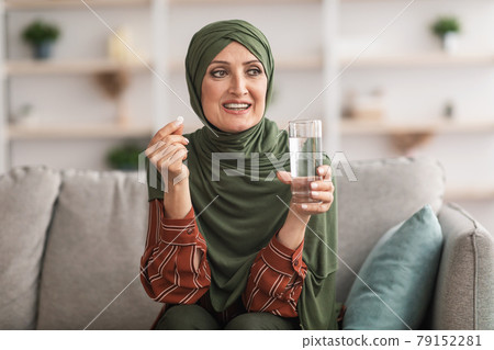 Senior Muslim Woman Holding Pill And Glass Of Water Indoors 79152281