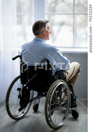 Full length of impaired senior man in wheelchair feeling depressed, suffering from loneliness in retirement home 79152284