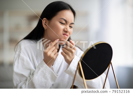 Young asian lady in bathrobe removing black heads Young asian lady in bathrobe removing black heads 79152316