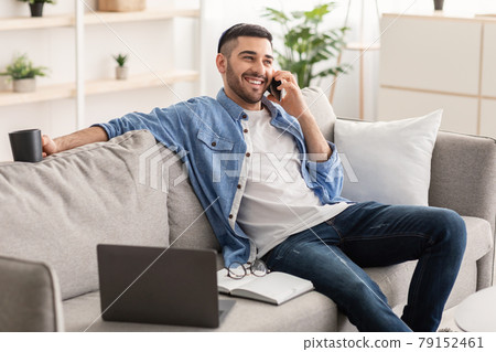 Smiling jew man working and talking on cellphone at home Smiling jew man working and talking on cellphone at home 79152461