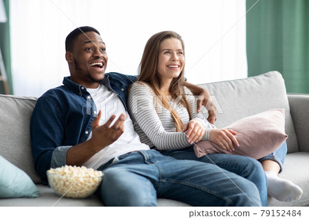 Weekend Leisure. Interracial Couple Watching Tv And Resting On Sofa At Home Weekend Leisure. Interracial Couple Watching Tv And Resting On Sofa At Home 79152484