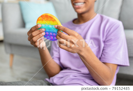 Unrecognizable black teen guy using POP IT toy to relieve stress at home, closeup Unrecognizable black teen guy using POP IT toy to relieve stress at home, closeup 79152485