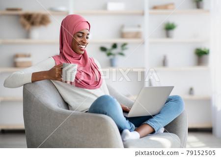 Black Woman In Hijab Resting With Laptop And Coffee At Home Black Woman In Hijab Resting With Laptop And Coffee At Home 79152505