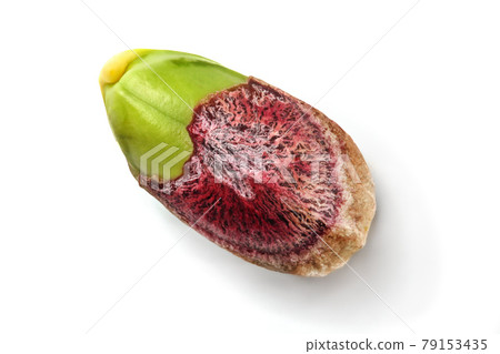 Detail of single pistachio nut, partial peeled, green kernel visible under purple skin, isolated on white background. 79153435