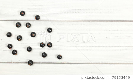 Tabletop view blackcurrants scattered on white boards, space for text on right side. Tabletop view blackcurrants scattered on white boards, space for text on right side. 79153449