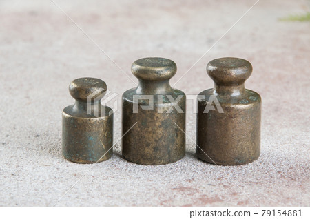 Three antique bronze weights for scales on concrete background. Three antique bronze weights for scales on concrete background. 79154881