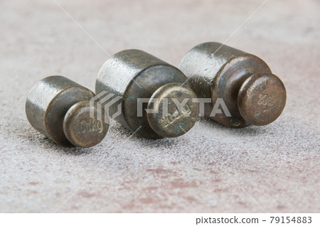 Three antique bronze weights for scales on concrete background. Three antique bronze weights for scales on concrete background. 79154883