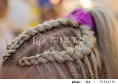 Women's hands weave a pigtail on the brunette's head. Women's hands weave a pigtail on the brunette's head. 79155219