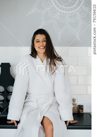 Elegant smiling woman in white coat posing in the kitchen 79156610