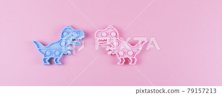 Banner. Two silicone fidget toys pop it in shape of dinosaur on the pink background. Banner. Two silicone fidget toys pop it in shape of dinosaur on the pink background. 79157213