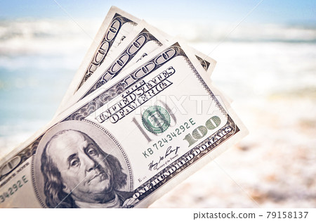 Girl holding money bill of 300 dollars on background of sea ocean Girl holding money bill of 300 dollars on background of sea ocean 79158137