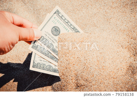 A girl takes out from the sand money notes of three hundred dollars. A girl takes out from the sand money notes of three hundred dollars. 79158138