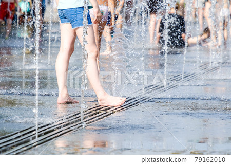 Feet of a woman barefoot in the spray of jets of water from the fountain. Feet of a woman barefoot in the spray of jets of water from the fountain. 79162010