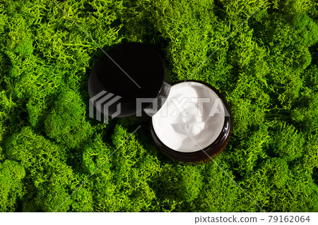 Jar of beauty cream on green moss background in the morning rays of light. Organic clay mask cream for the face and body. Concept of skincare cosmetic, spa and wellness center, facial treatment Jar of beauty cream on green moss background in the morning rays of light. Organic clay mask cream for the face and body. Concept of skincare cosmetic, spa and wellness center, facial treatment 79162064
