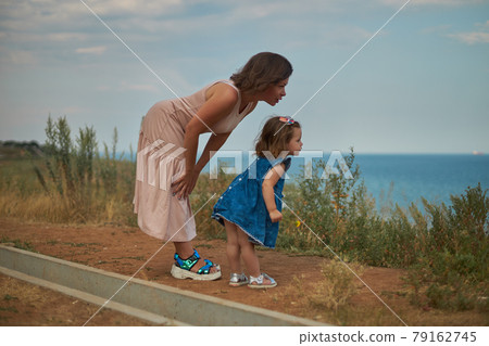 Mother leaned over to her daughter and talks about something Mother leaned over to her daughter and talks about something 79162745